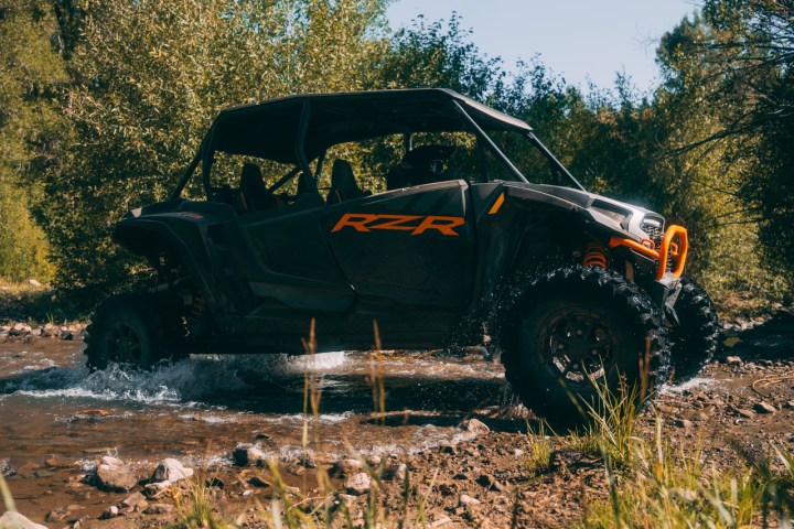 a polaris utv driving through a stream
