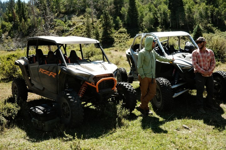 two guys next to some side by sides