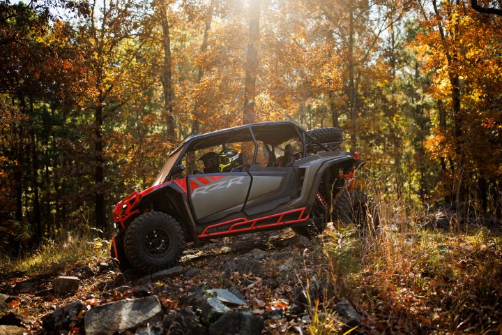 All-terrain vehicle driving on rocky forest path in autumn.