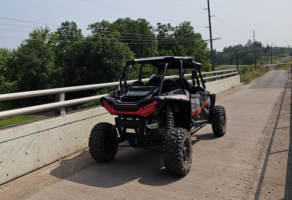 All-terrain vehicle on a concrete bridge with trees in background.