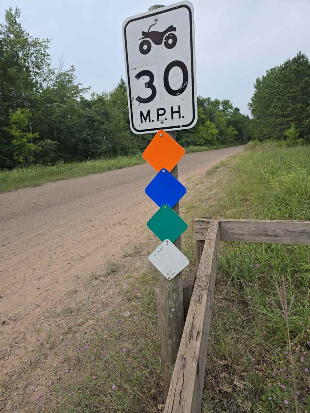 30 MPH sign with colored diamond markers on rural dirt road.